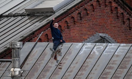 Joe Outlaw sits astride a roof in the rain with ‘FREE’ painted on it