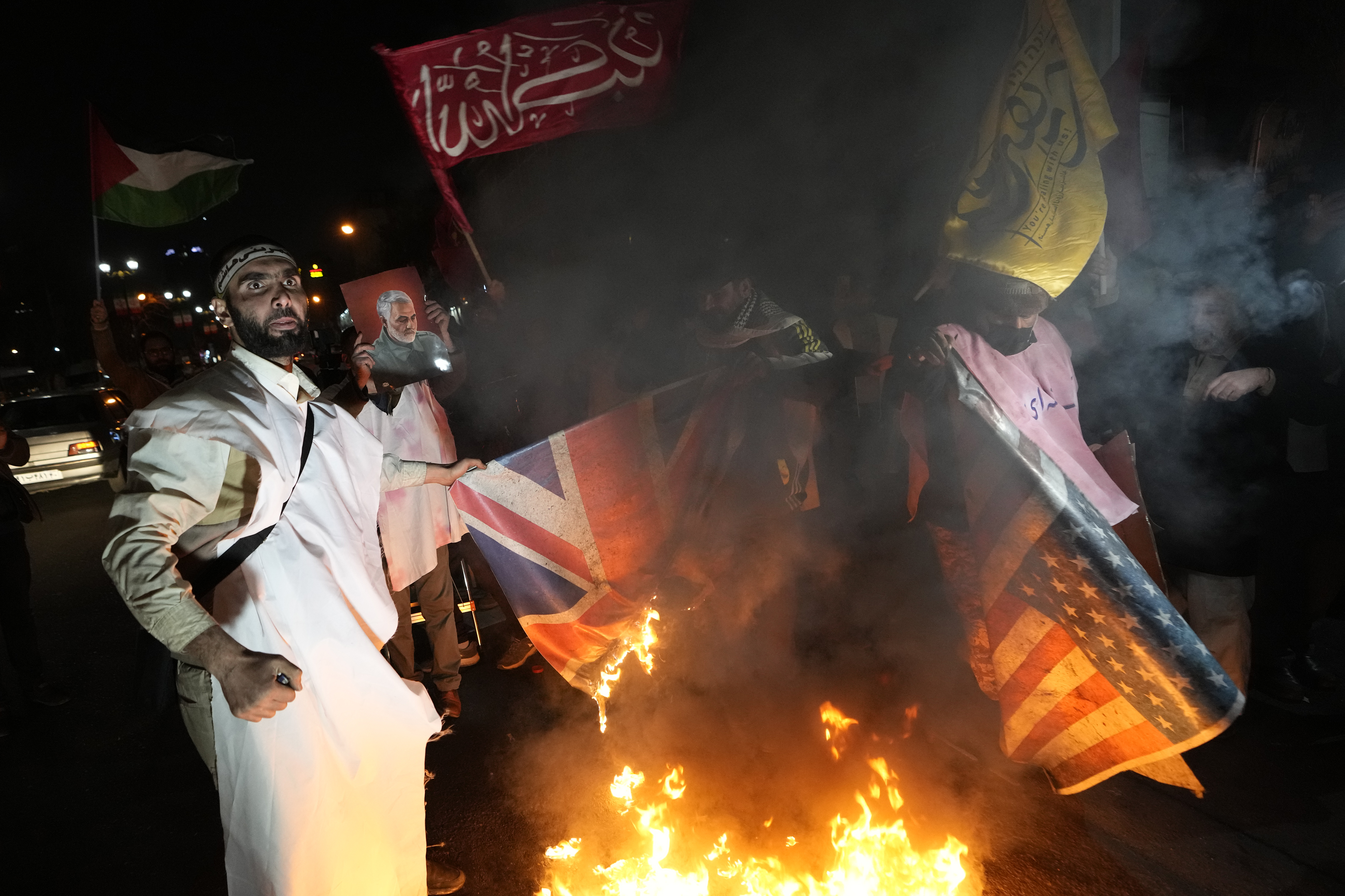 Protesters burn flags outside the British embassy in Tehran, Iran