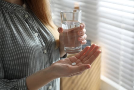 Posed by a model Young woman with abortion pill and glass of water indoors, closeup