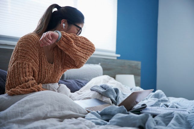 A woman coughing in bed.