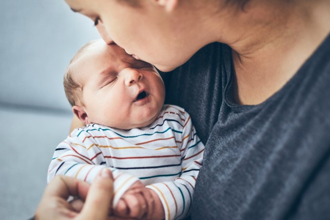 Mother with newborn. Woman kissing her 4 days old son at home.