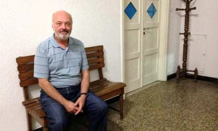 Carlos Luis Malatto sitting on a wooden bench in a house