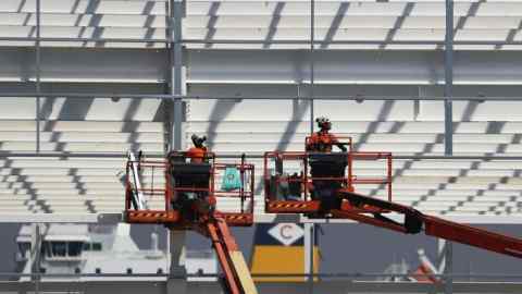 Builders in 2020 work from cherry pickers on the largest warehouse in Europe, owned and developed by Tritax Big Box, in Dartford, UK