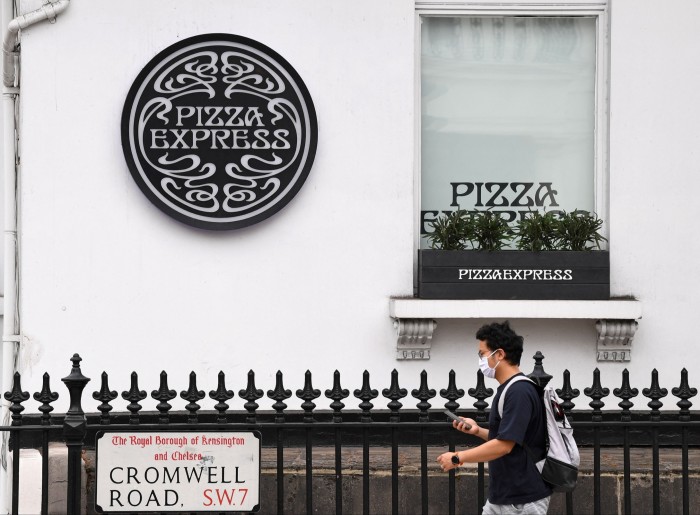 A man wearing a face mask  walks past a PizzaExpress restaurant in London at the height of the pandemic