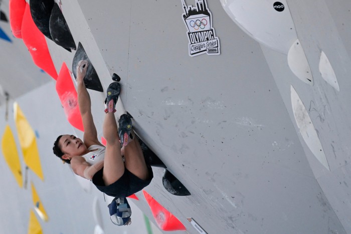 View looking up at a female climber on a bouldering wall