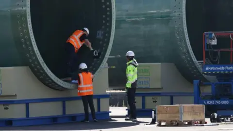 Getty Images Workers inspect a wind turbine