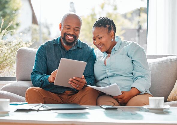 Senior couple looking through their bills while using a digital tablet