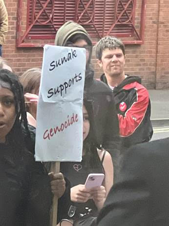 Labour councillor Dale Bilbie, right, is seen standing behind a sign accusing Rishi Sunak of supporting genocide