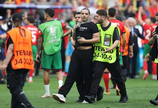 Stewards take a pitch invader off the pitch after attempting to get a picture with Cristiano Ronaldo 