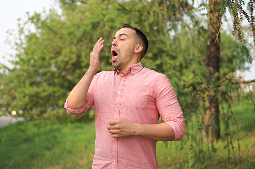 a man sneezes loudly in the park.