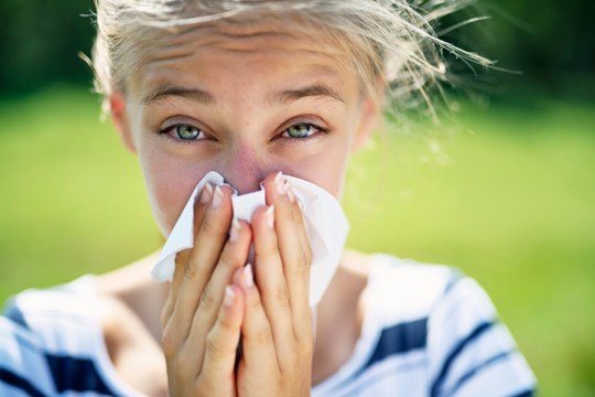 Teenage girl with allergy blowing nose