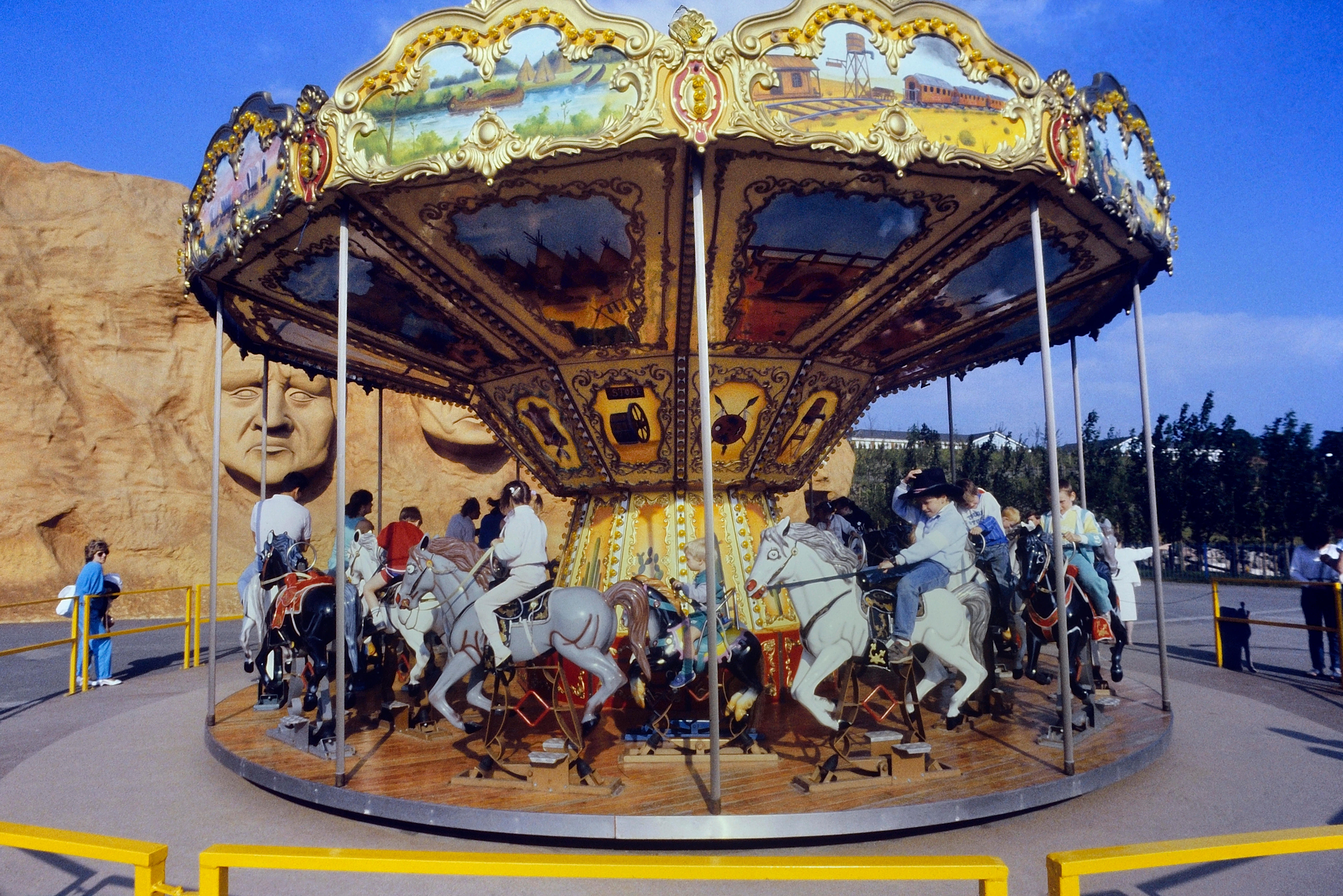 Children pictured enjoying a carousel ride with native heads in the background