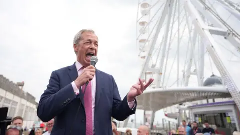 PA Media Nigel Farage holding a microphone on Clacton seafront