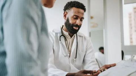 Getty Doctor talking to patient holding clipboard