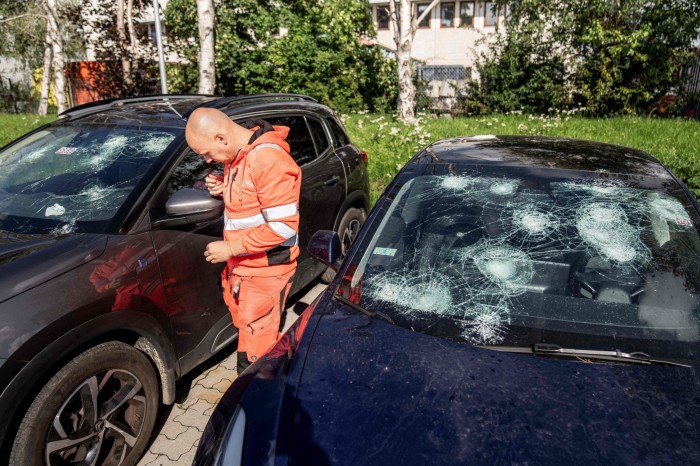 A man inspects a car which was damaged in connection with severe hail in northern Italy