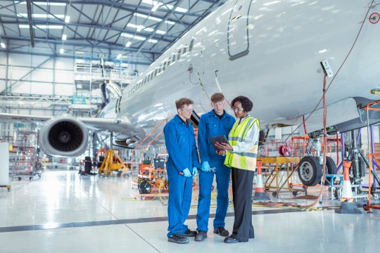 Apprentice aircraft maintenance engineers with supervisor in maintenance hangar