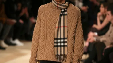 Reuters Model on fashion catwalk wearing a beige jumper with a Burberry check scarf