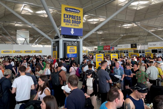 Passengers queue by the Ryanair check-in desk at London Stansted Airport.