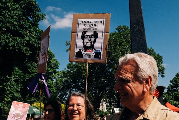 Feminist protestor holds a sign that says The Extreme Right Talks to You Every Day (L Extreme Droite Vous Parle Tous Les Jours in french) with the names of the media C8 CNews Europe1 and the head of Vincent Bollore