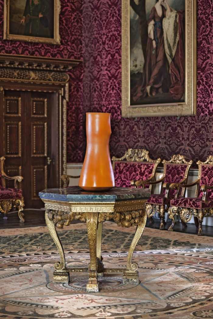 An orange sculpture on a table in a room with ornate and antique furniture