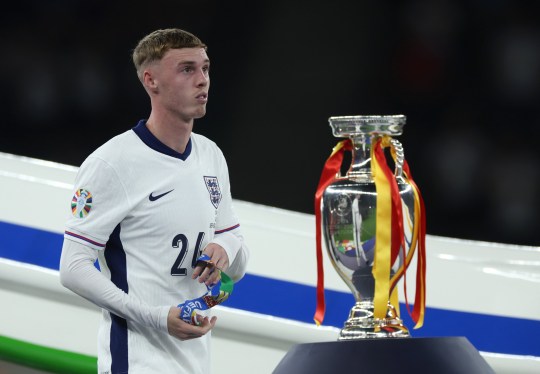 Cole Palmer of England walks past the UEFA EURO 2024 trophy following the UEFA EURO 2024 final match between Spain and England at Olympiastadion