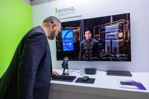 Getty Images A convention attendee stands in front of a screen displaying a CPU-controlled character in a 3D environment. The man in front of the screen is leaning over a keyboard. A sign above the screen reads "bring characters to life with on-device AI models".