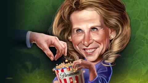 A middle-aged woman holds a carton of pop corn with Paramount written on the label as a male hand reaches for the pop corn