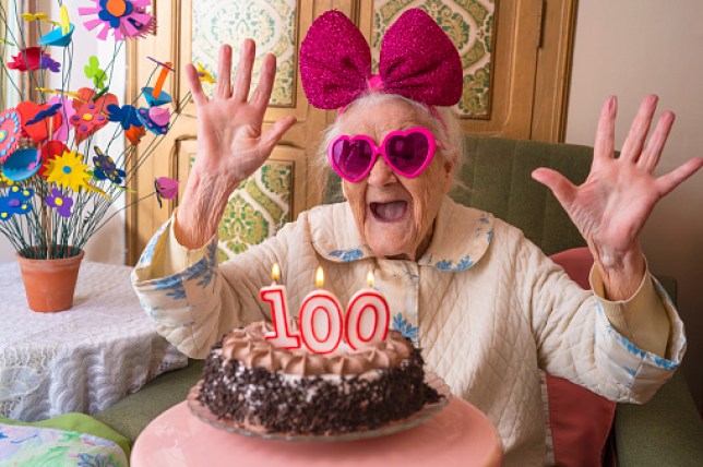 Woman with a cake with the number 100 as candles 