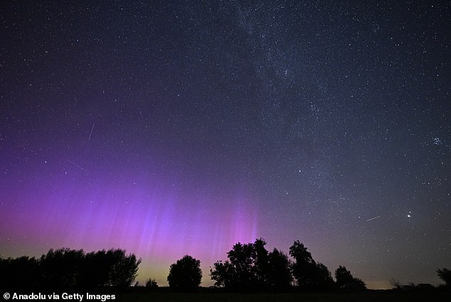 Stargazers in Brandenburg, Germany (pictured) spotted a shooting star from the Perseid Meteor Shower (right) appear during a particularly strong outburst of the Northern Lights