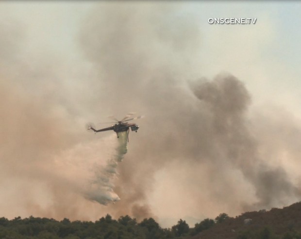 A helicopter drops water on the Tenaja fire burning near...