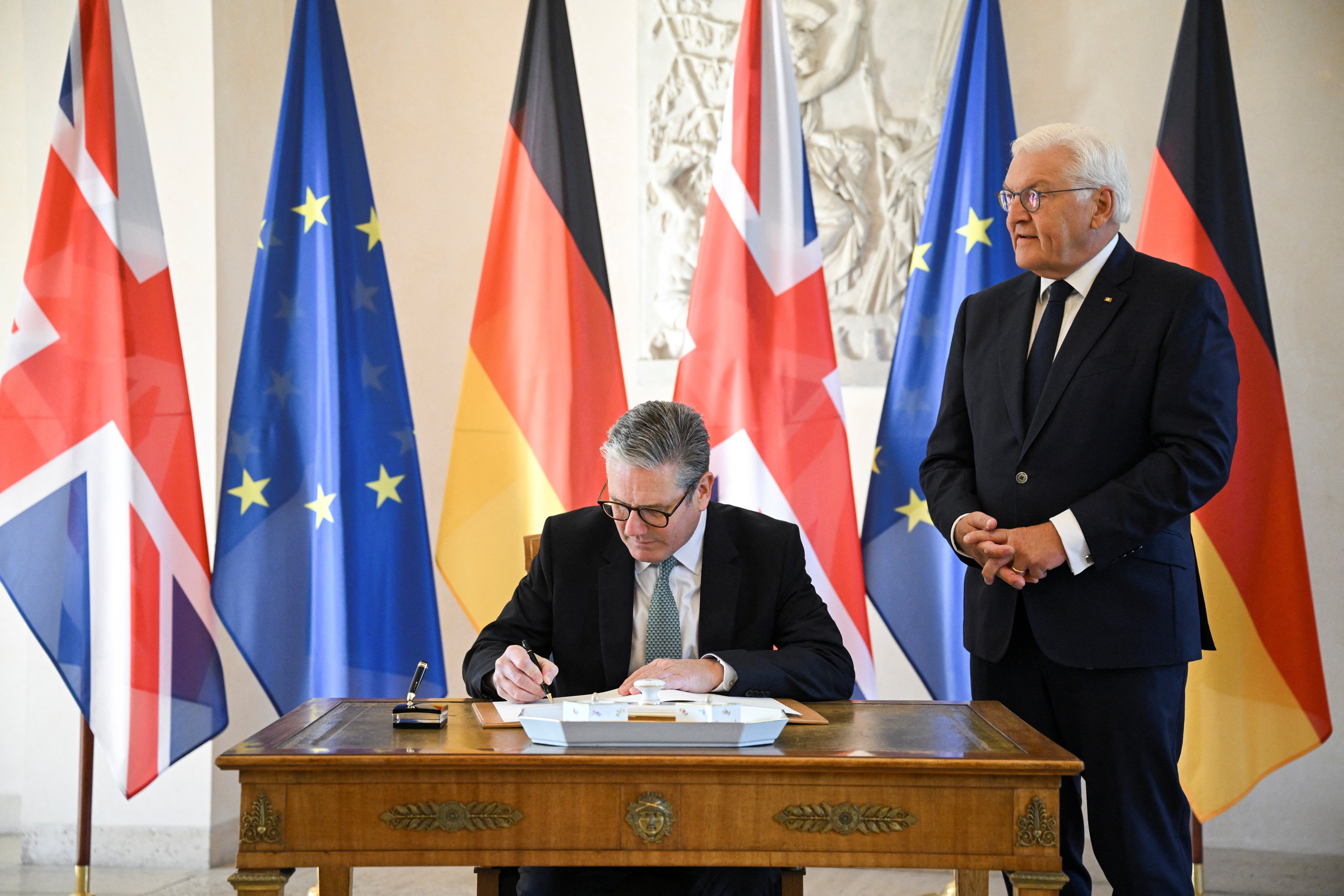 British Prime Minister Keir Starmer signs a guest book as he meets German President Frank-Walter Steinmeier at Bellevue Palace in Berlin, Germany