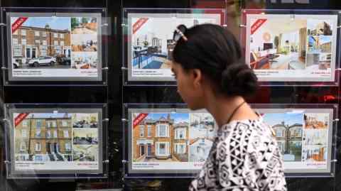 A woman looks over properties at an estate agents in London