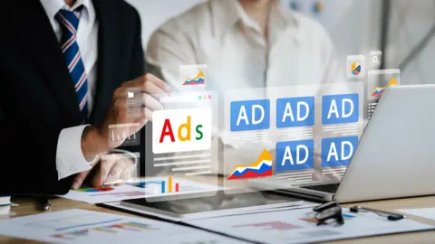 Getty Images A graphic illustration of online adverts floating above a laptop screen