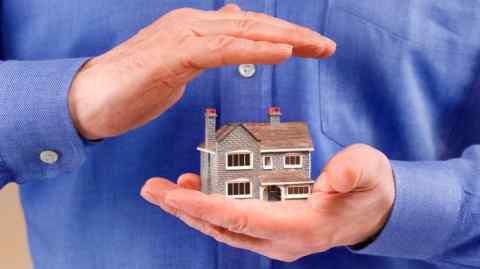 A man holds a model of a house in his palm