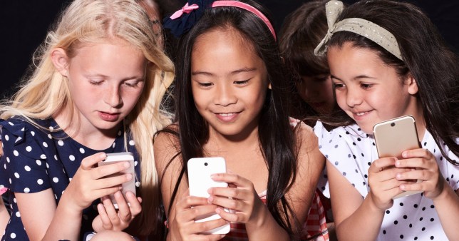 Three young girls holding smartphones.