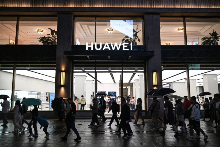 People walk past a Huawei shop in Shanghai