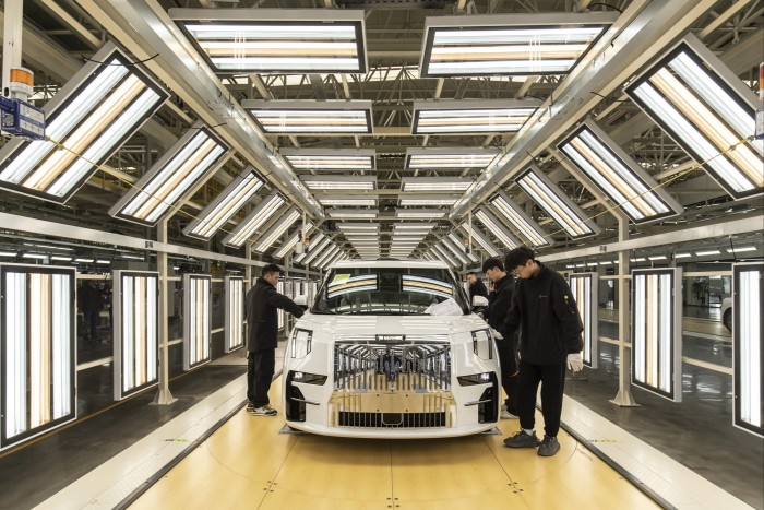 Workers assemble an electric car on a production line