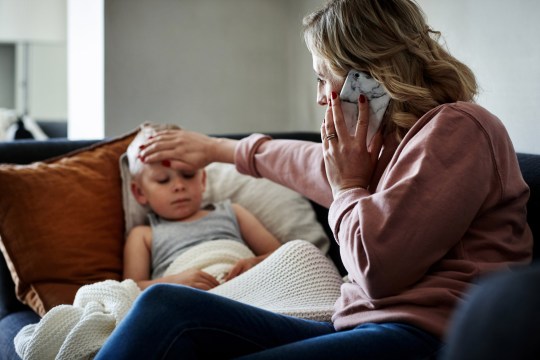 A mother with a sick child laying on bed with fever. 