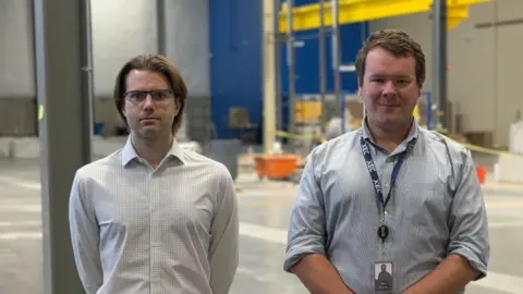 Xcimer Conner Galloway (left) and Alexander Valys stading in the big empty factory which will one day house their laser-based fusion project.