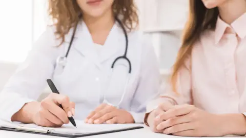 Getty Images Doctor writing notes on a young patient