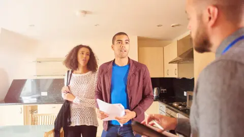 Getty Images A couple talking to an estate agent during a flat viewing