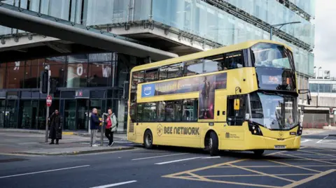 Getty Images Yellow double decker 'Bee Network' branded bus in Manchester city centre