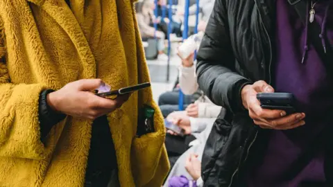 Getty Images Travellers use their mobile phones on a train