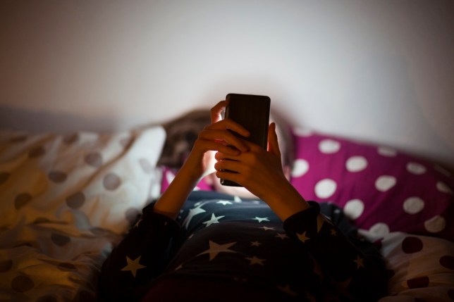 Child using a smartphone in bed 