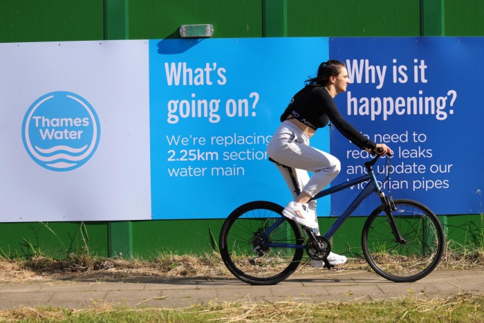 A woman passes a Thames Water construction site in London