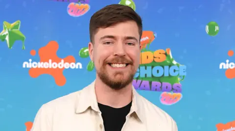 Getty Images MrBeast pictured at Nickelodeon's 2023 Kids' Choice Awards wearing a cream overshirt over a black top. 