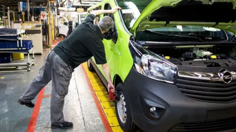 Getty Images A male employee checks the front wheel of a green Opel Vivaro medium sized van on the final assembly line at the Vauxhall plant in Luton, UK.