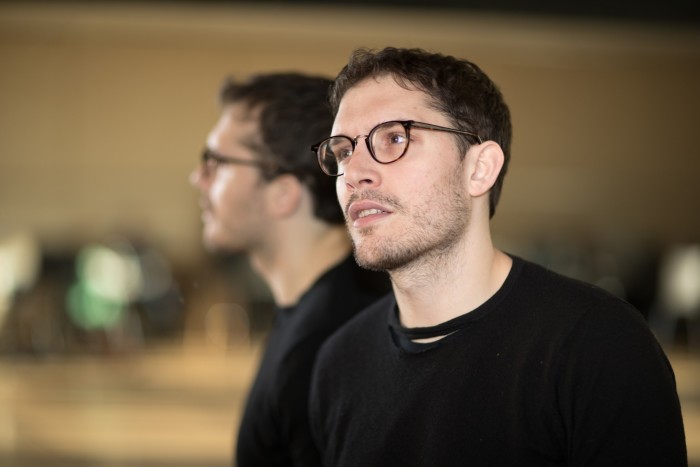 A head and shoulders shot of a man with short dark hair and glasses