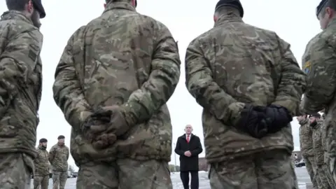 Reuters Soldiers stand in a circle listening to a man wearing a tie - the UK's defence secretary John Healey