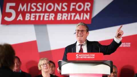 Keir Starmer speaking at a press conference with a ‘5 Missions For A Better Britain’ logo in the background